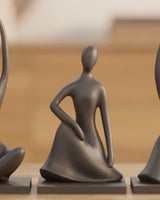 Trois figurines humaines abstraites à finition mate réunies sur une surface blanche