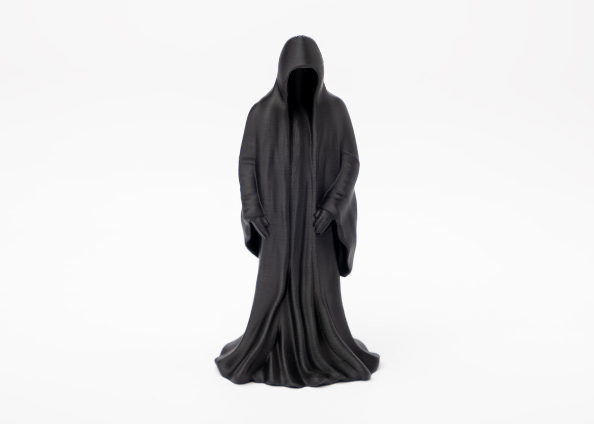 Figurine gothique de la Mort sur une étagère en bois foncé près de bougies et de plantes séchées