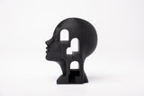 Buste architectural surréaliste sur une bibliothèque minimaliste avec objets décoratifs naturels