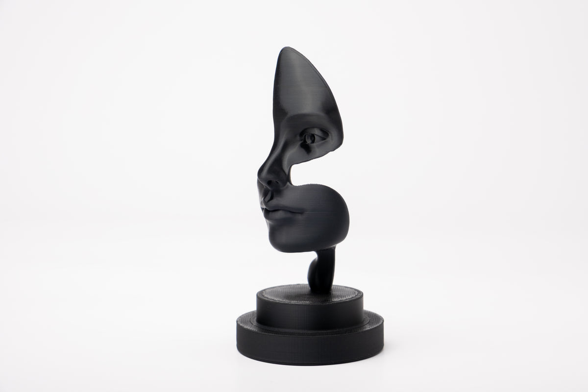 Note of Emotion – sculpture noire abstraite sur une étagère minimaliste avec des livres et une bougie