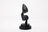 Note of Emotion – sculpture noire abstraite sur une étagère minimaliste avec des livres et une bougie