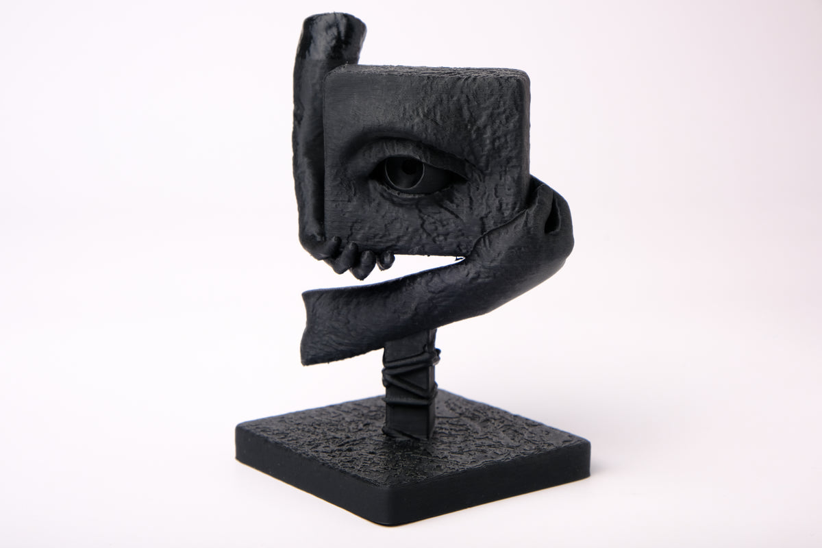 The Witness – sculpture surréaliste sur un bureau en bois sombre avec décoration minimaliste