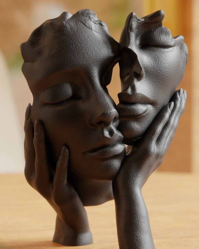 Sculpture abstraite noir mat de deux visages qui se touchent, vue de face