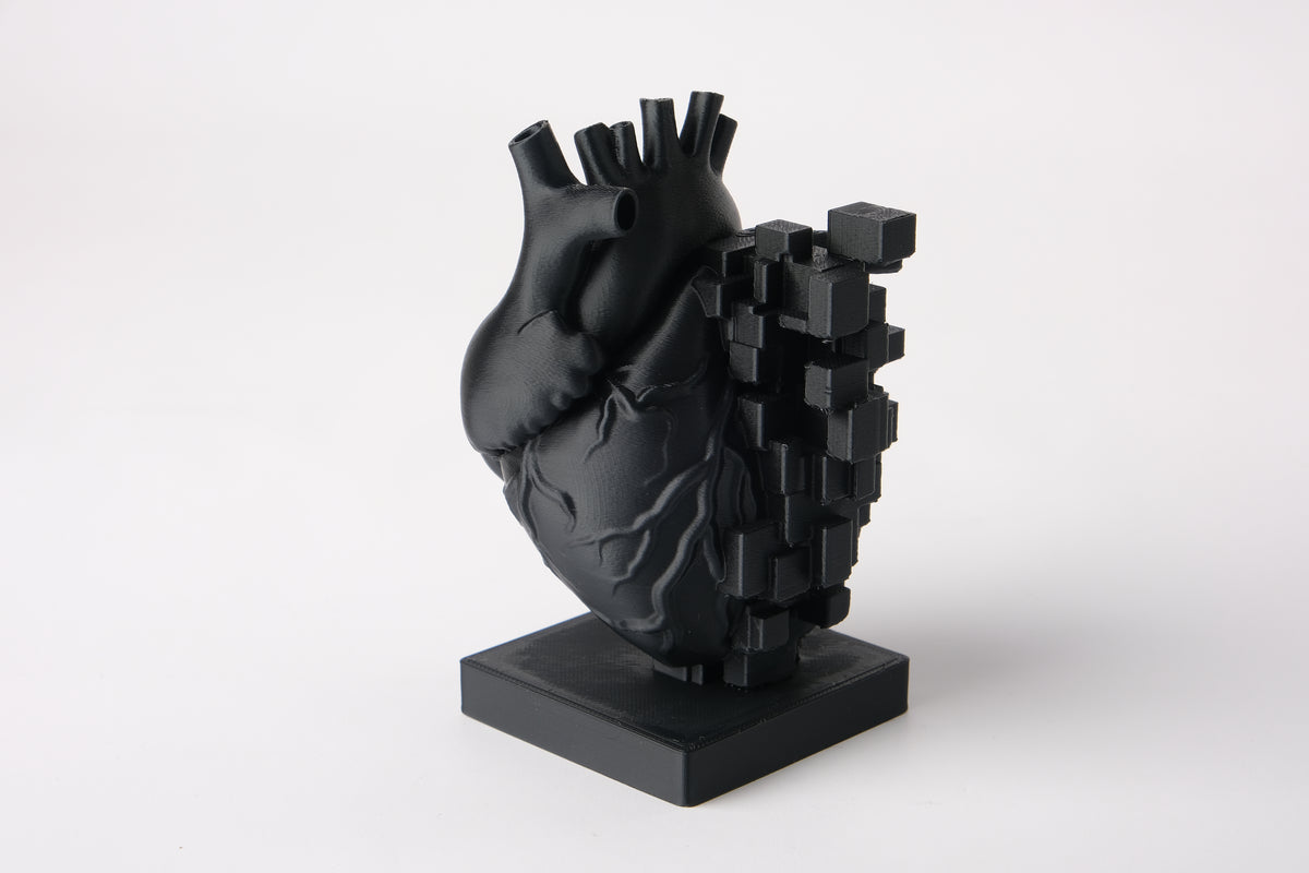 Sculpture de cœur pixelisé sur un bureau en bois à côté de livres et d'une petite plante