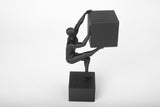 Sculpture humaine abstraite sur un bureau en bois près de livres et d'un mug en céramique dans une pièce minimaliste