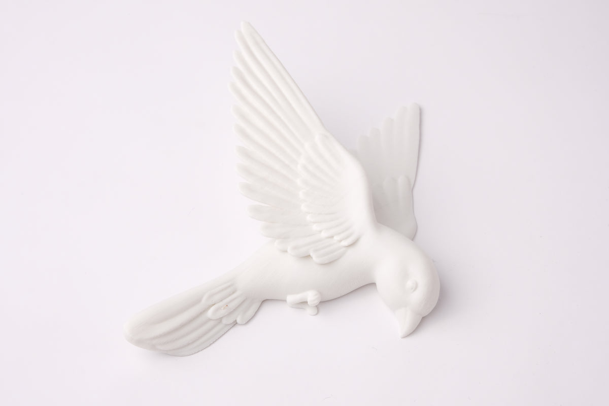 Sculpture murale blanche minimaliste avec des oiseaux sur un mur de salon gris chaud