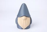 Figurine de lutin sur une bibliothèque près de bougies et d'une petite plante dans un intérieur cosy