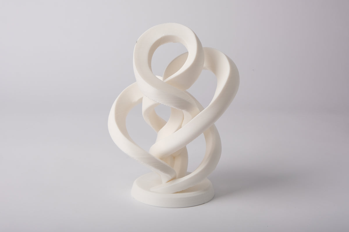 Sculpture abstraite de l'infini minimaliste sur une étagère en bois clair avec une déco neutre