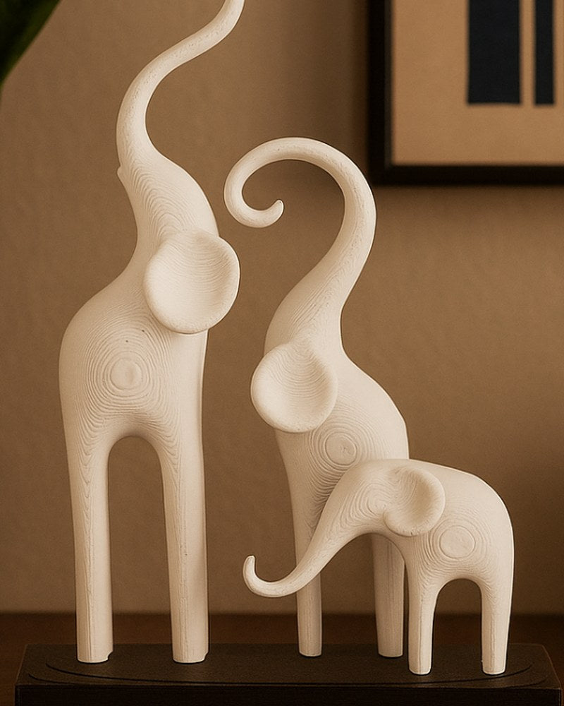 Sculpture d'éléphants minimaliste à trois figures stylisées sur socle sombre, fond blanc, gros plan