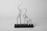 Sculpture minimaliste d'une famille d'éléphants sur une étagère en bois clair avec une déco scandinave neutre