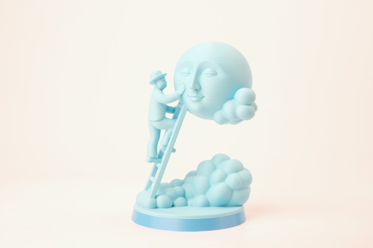 Sculpture Moon Caretaker sur une étagère minimaliste entre des livres et une petite plante