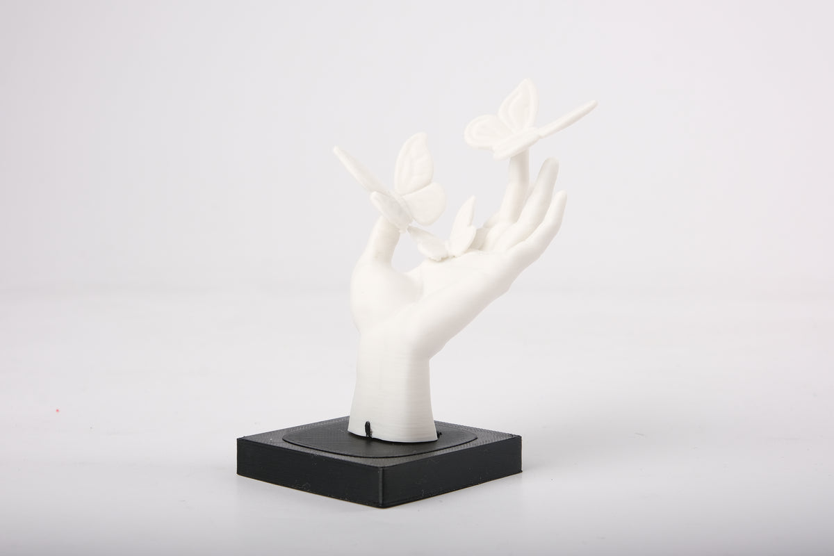 Sculpture de main aux papillons sur une étagère minimaliste en bois près d'un petit vase en céramique