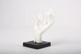 Sculpture de main aux papillons sur une étagère minimaliste en bois près d'un petit vase en céramique