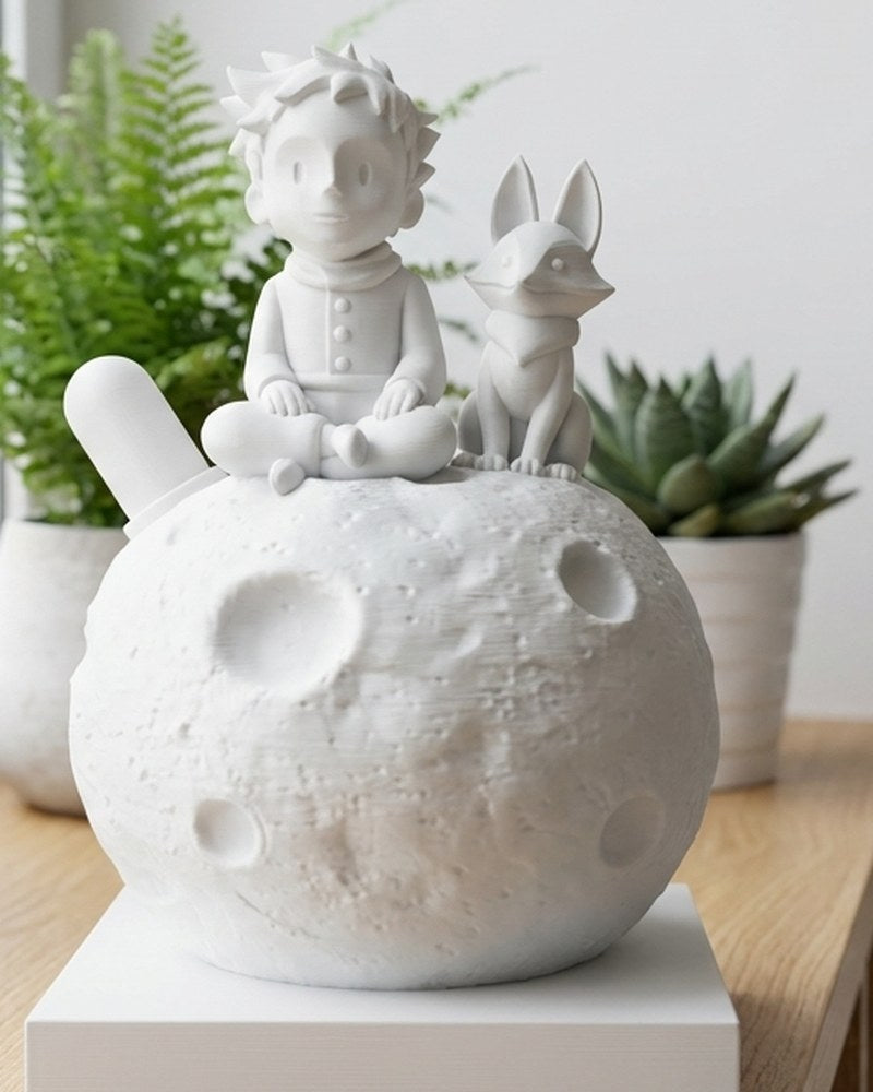 Le Petit Prince sur la Lune avec la figurine du renard sur une surface blanche, vue de face