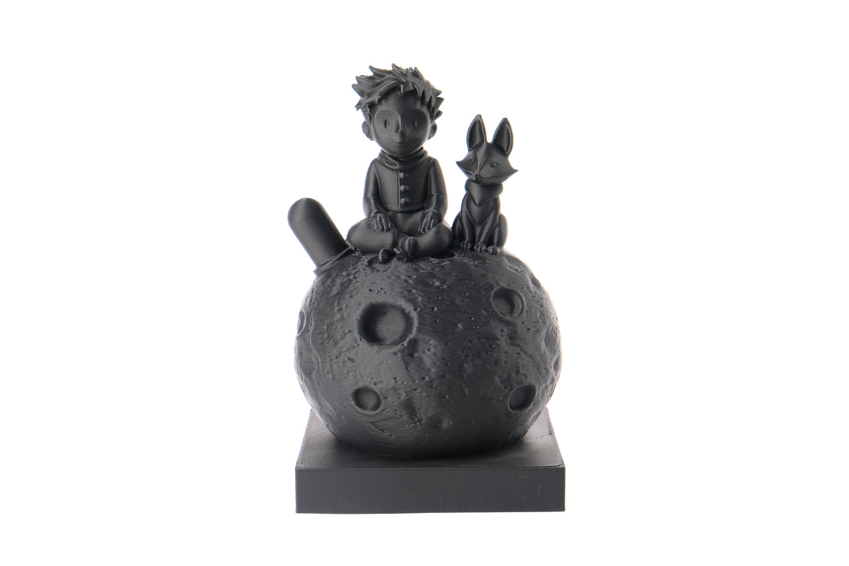 Sculpture du Petit Prince et du renard sur une bibliothèque en bois à côté de livres