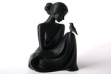 Sculpture de femme Bird Whisperer sur une étagère en bois avec plantes séchées