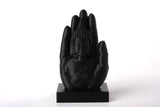 Sculpture de main de Bouddha sur une étagère en bois près de bougies et de plantes séchées dans un coin méditation paisible
