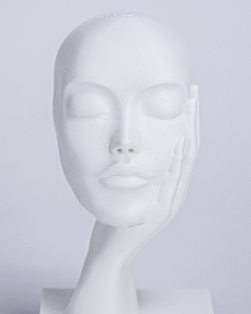 Gros plan de la sculpture de visage Dreamer's Rest, yeux fermés et main contre la joue