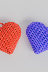Gros plan d'un porte-clés cœur tricoté double face, rouge chaud, à la douce texture tissée