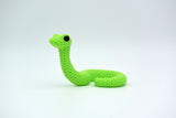 Petit serpent façon tricot sur une étagère en bois près de plantes et de livres, intérieur scandinave