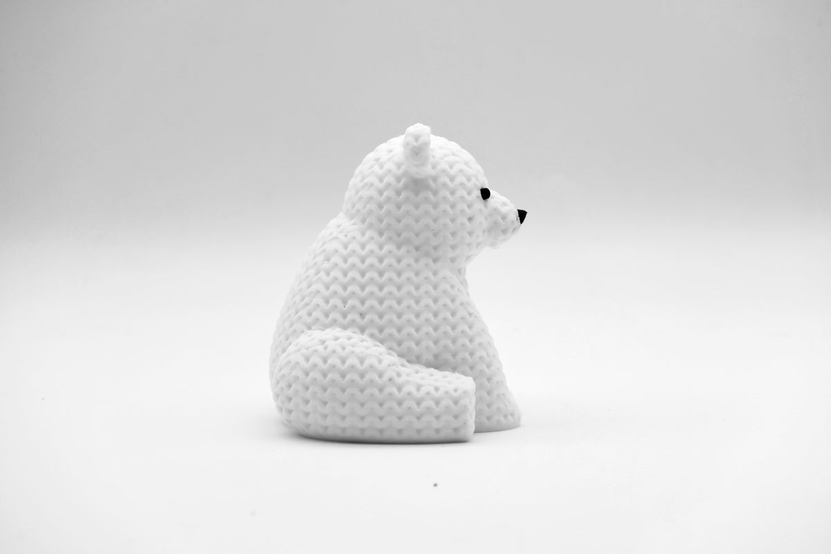 Gros plan d'une petite figurine d'ours polaire tricoté blanc, aspect crocheté, 8 cm de haut
