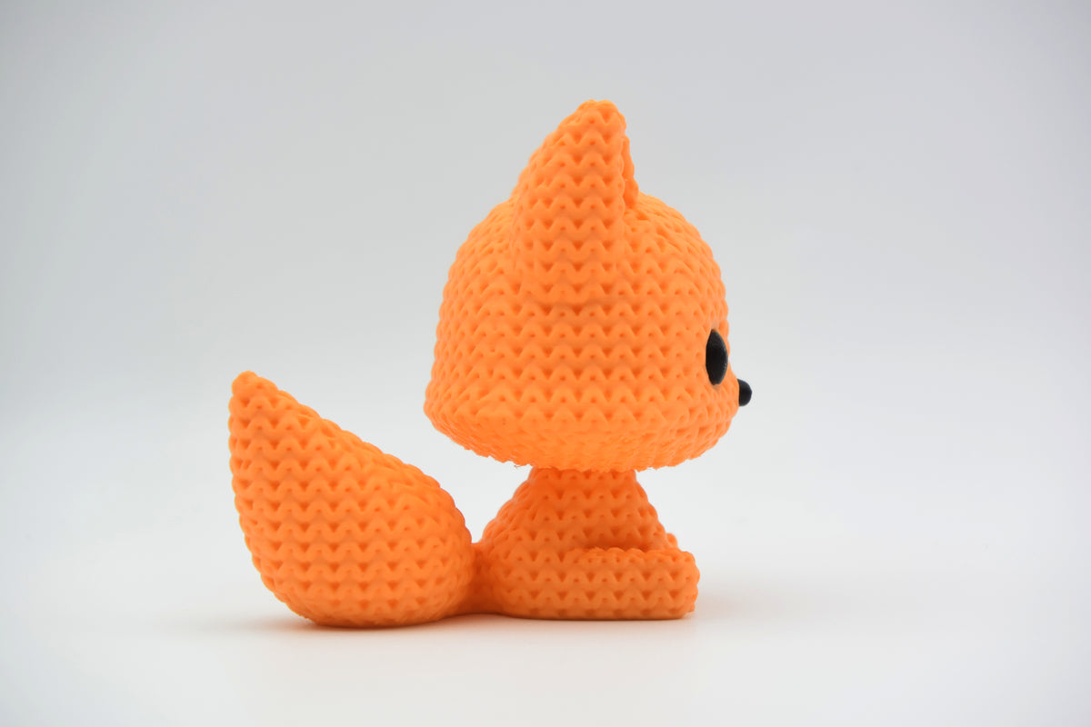 Petite figurine renard façon tricot sur une étagère en bois près de livres et d'une plante, intérieur scandinave