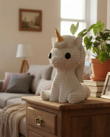 Gros plan d'une petite licorne tricotée blanche à corne dorée, aspect crocheté, 65 mm de haut