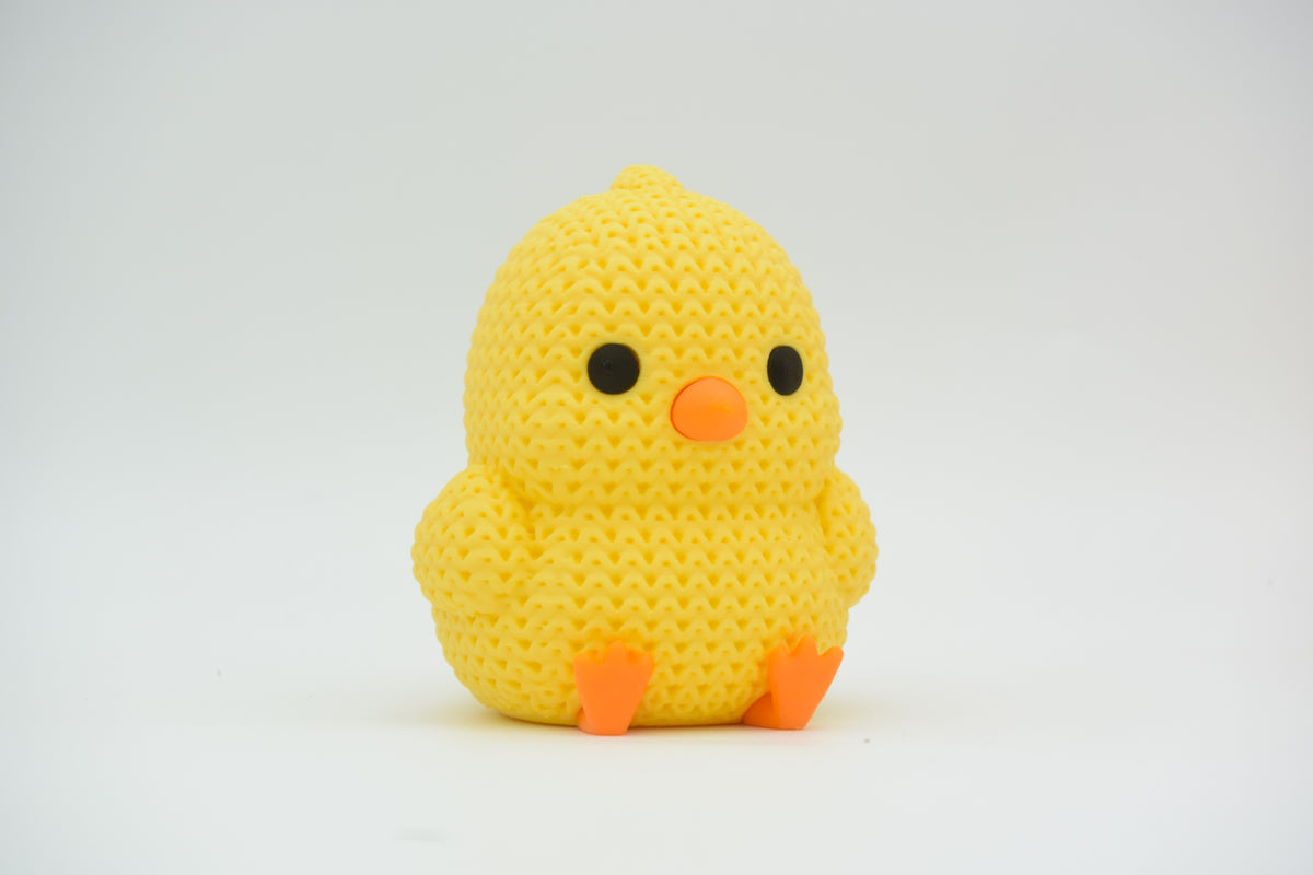 Gros plan d'un petit poussin tricoté jaune au bec et aux pattes orange