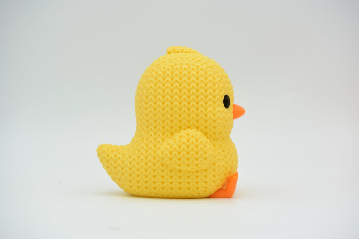 Gros plan d'un petit poussin tricoté jaune au bec et aux pattes orange