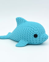Gros plan d'une petite figurine de dauphin tricoté à texture crochetée et yeux ronds rapportés
