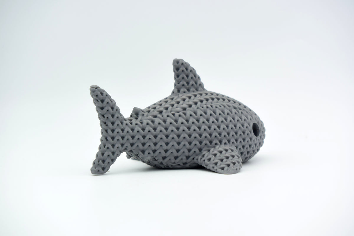 Requin tricoté décoratif sur une étagère en bois à côté de livres et de petites plantes dans un intérieur scandinave