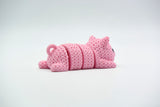 Porte-clés cochon tricoté articulé sur un trousseau, posé sur une table en bois dans un intérieur lumineux