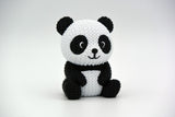 Figurine de panda tricotée sur une étagère en bois à côté de plantes et d'une déco neutre