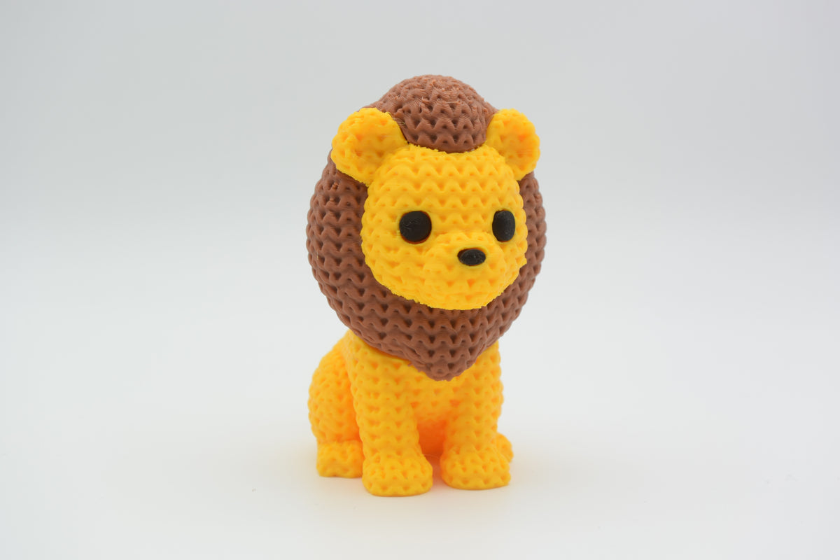Petit lion façon tricot sur une étagère en bois près d'une plante et d'accessoires déco neutres