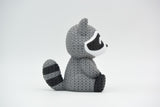 Gros plan d'une figurine de raton laveur tricoté, aspect crocheté détaillé, sur fond blanc