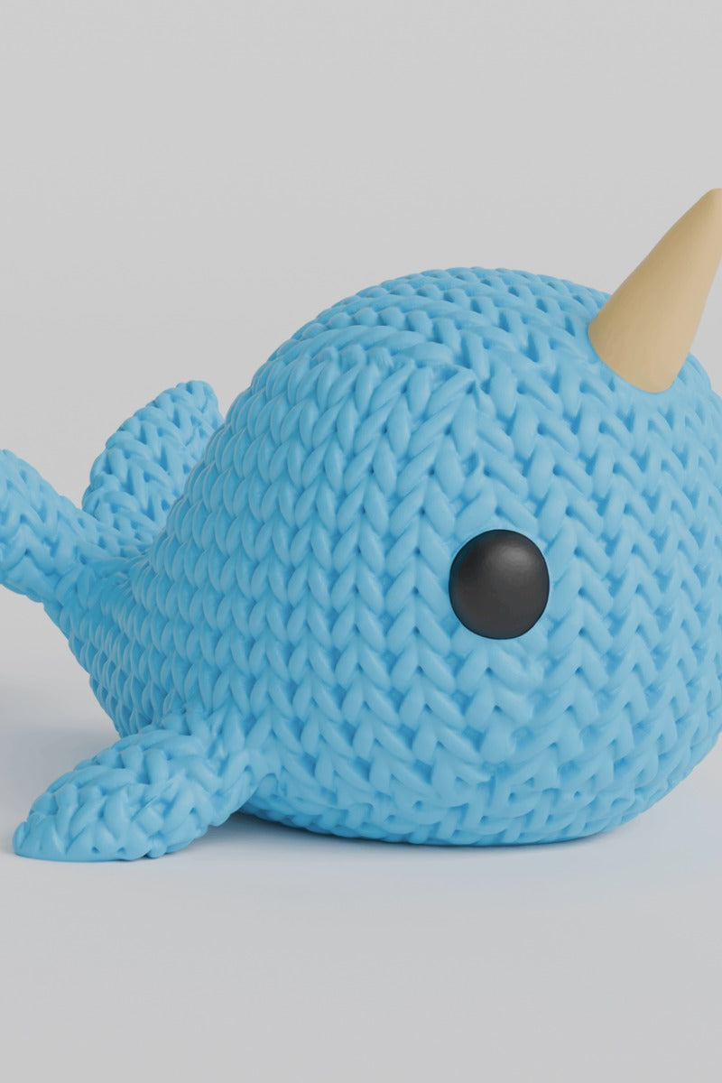 Gros plan d'une figurine de narval tricoté à texture crochetée et défense torsadée en spirale