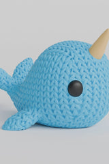 Gros plan d'une figurine de narval tricoté à texture crochetée et défense torsadée en spirale
