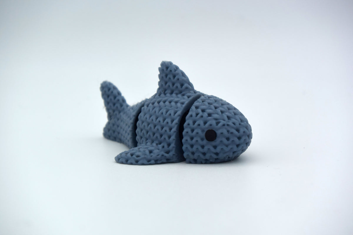 Gros plan d'un requin tricoté articulé à texture crochetée sur surface blanche
