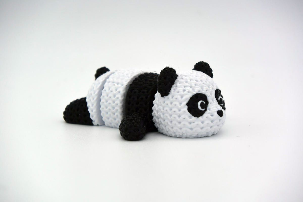 Petit panda façon tricot sur une étagère en bois près de livres et d'une plante, décor scandinave