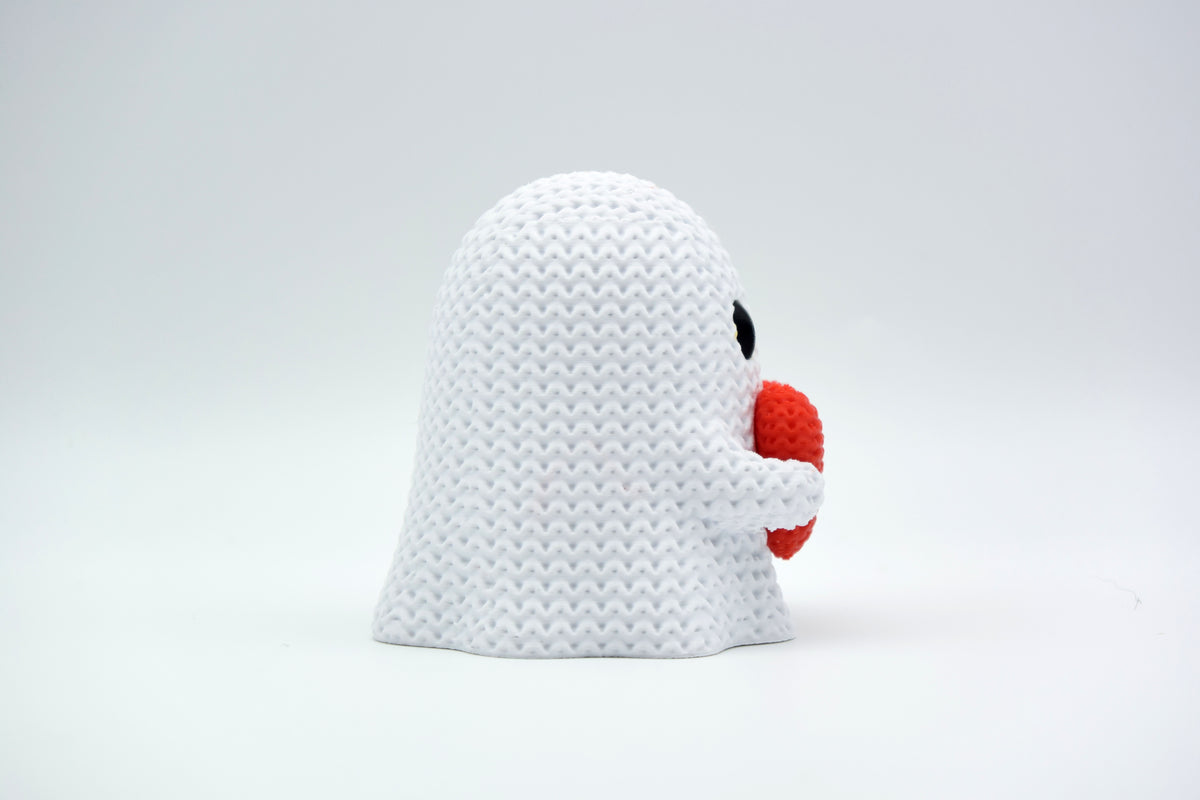 Petit fantôme façon tricot avec cœur sur une étagère en bois parmi des décorations d'automne