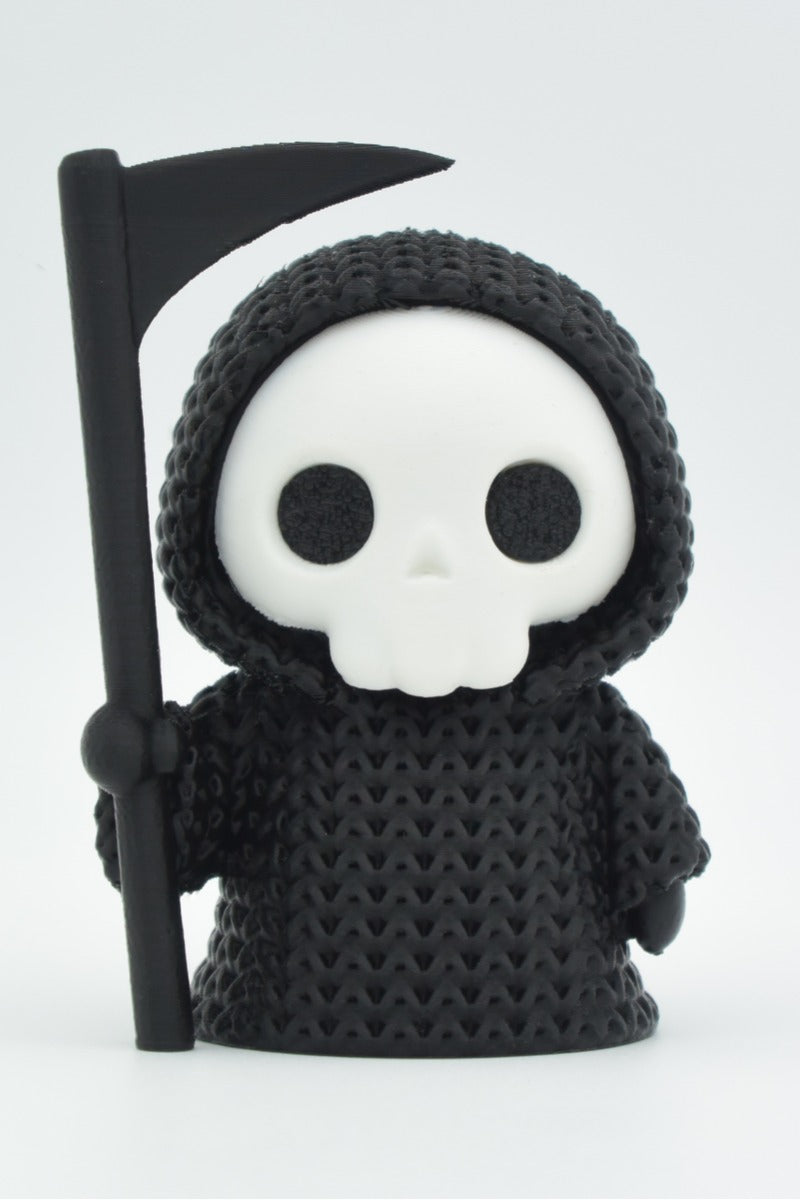 Gros plan d'une Faucheuse tricotée en cape à capuche avec sa faux, douce texture crochetée