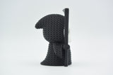 Petite Faucheuse façon tricot pour Halloween sur une étagère en bois sombre près de feuilles d'automne