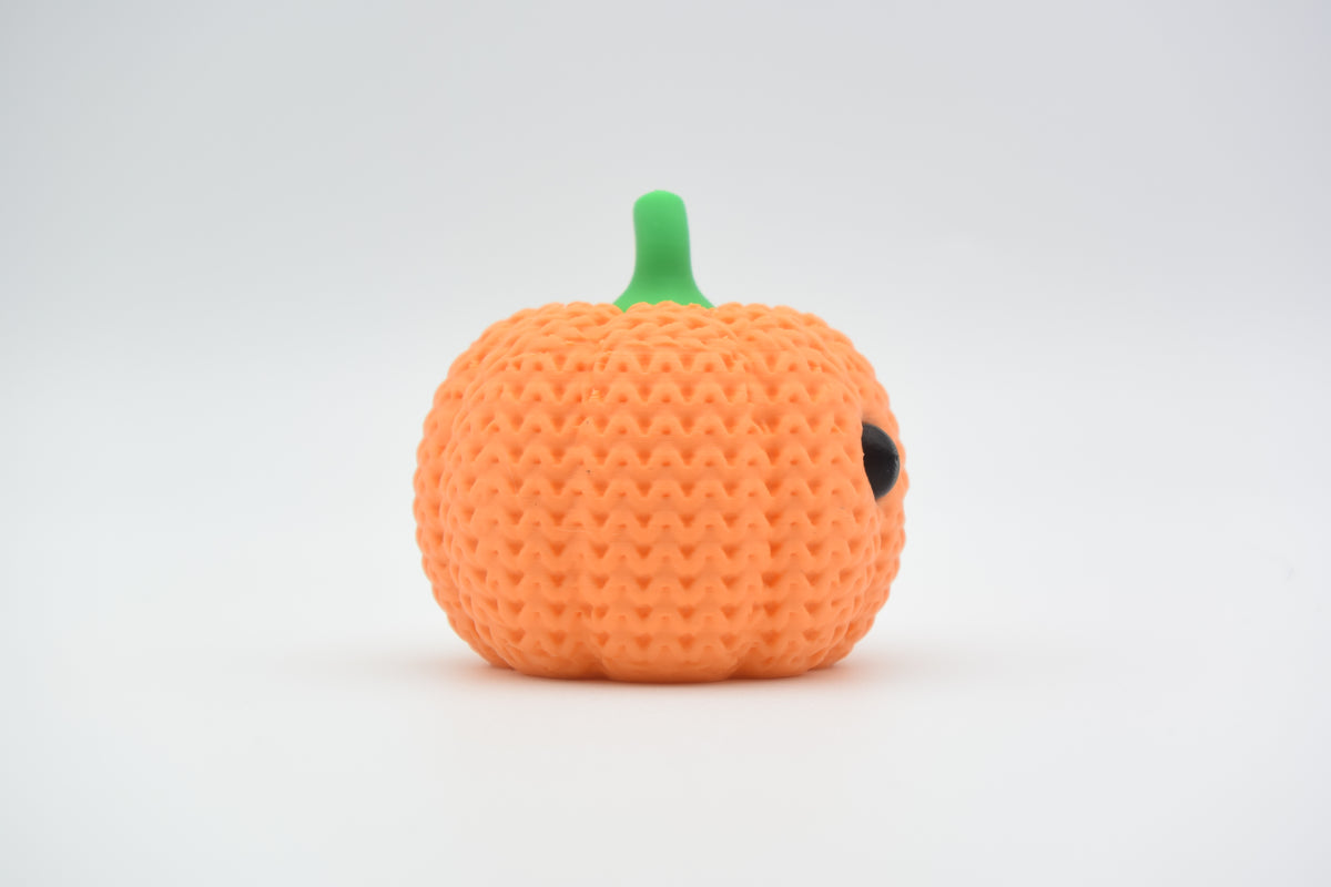 Décoration citrouille crochetée sur une étagère en bois près de feuilles d'automne et d'une petite bougie, ambiance chaleureuse