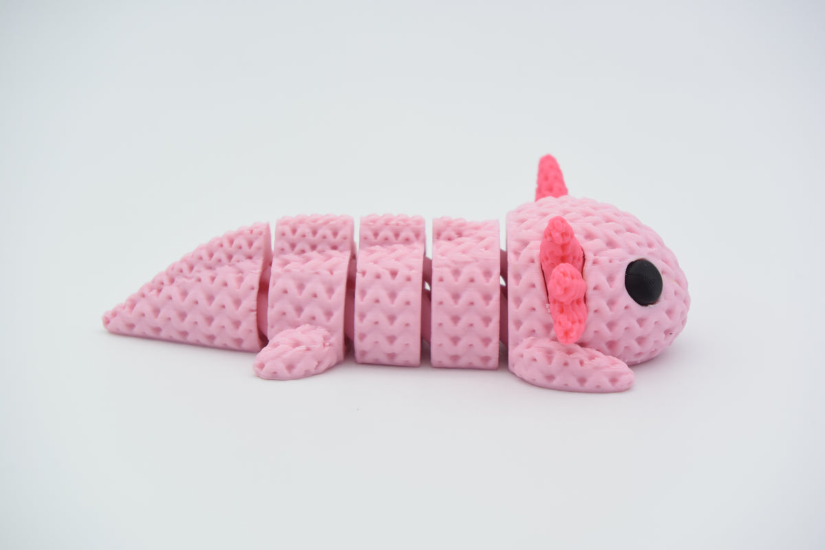 Axolotl tricoté articulé sur une étagère en bois près d'une petite plante
