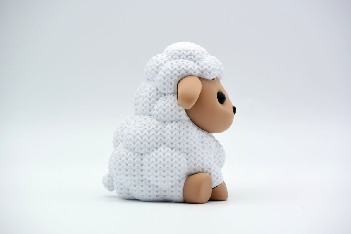 Mouton tricoté décoratif sur une étagère en bois à côté d'une petite plante et d'accessoires déco neutres