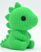 Gros plan d'un stégosaure tricoté vert à texture crochetée et petits yeux peints