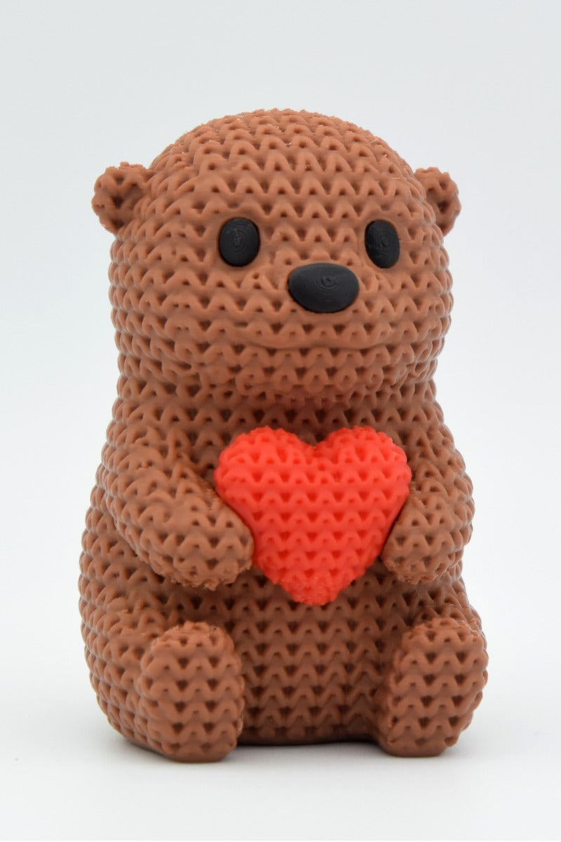 Gros plan d'une figurine de loutre crochetée avec un petit cœur et une douce texture tricotée