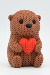Gros plan d'une figurine de loutre crochetée avec un petit cœur et une douce texture tricotée