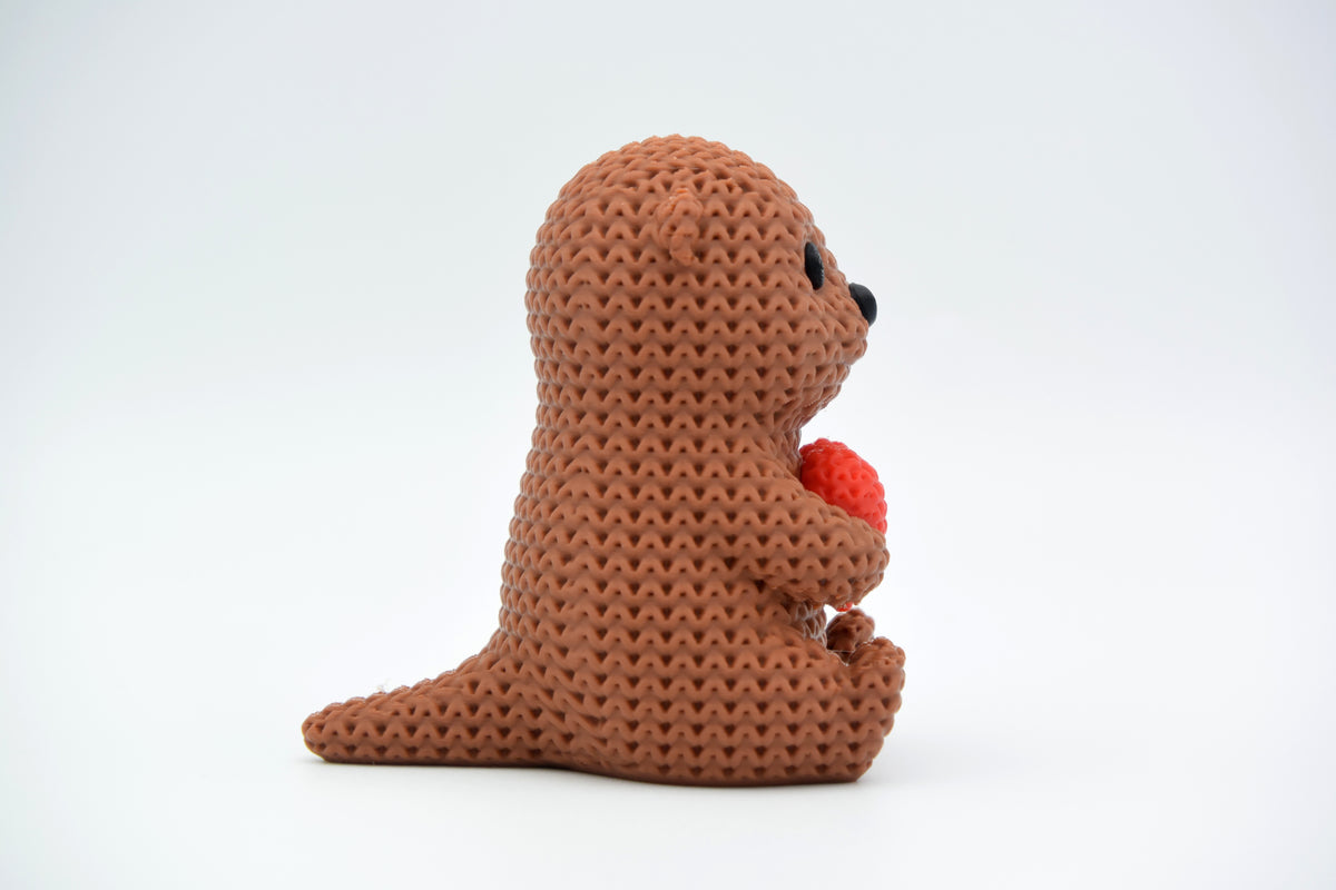 Gros plan d'une figurine de loutre crochetée avec un petit cœur et une douce texture tricotée
