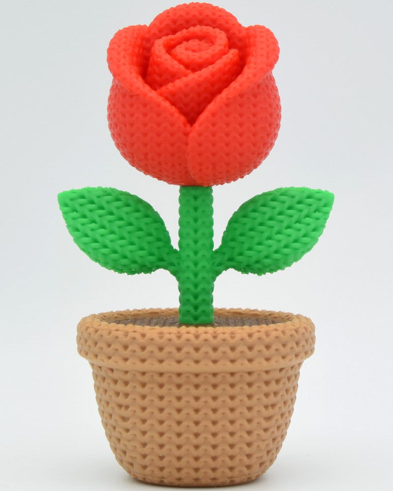 Gros plan d'une rose tricotée décorative aux pétales doux dans des tons rouges chaleureux